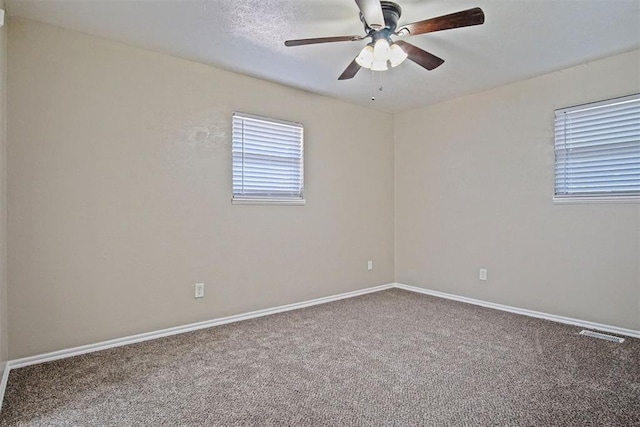 empty room featuring baseboards, a ceiling fan, visible vents, and carpet