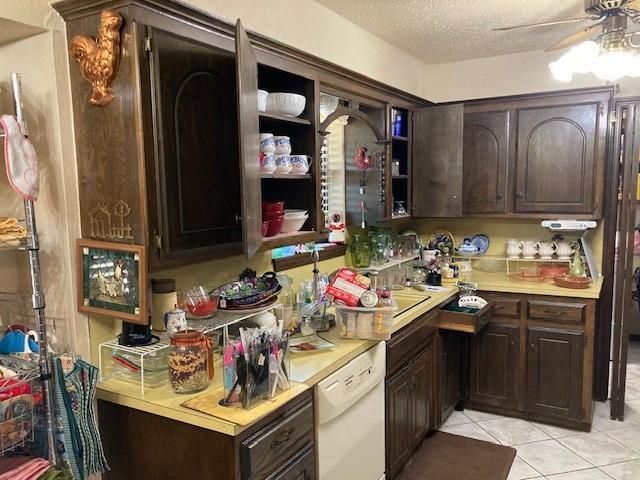 kitchen with light tile patterned floors, light countertops, dark brown cabinets, white dishwasher, and a ceiling fan