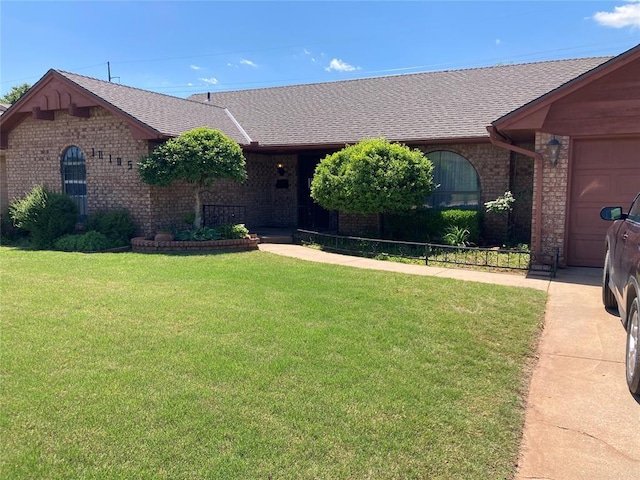 view of front facade featuring brick siding, roof with shingles, a front yard, and a garage