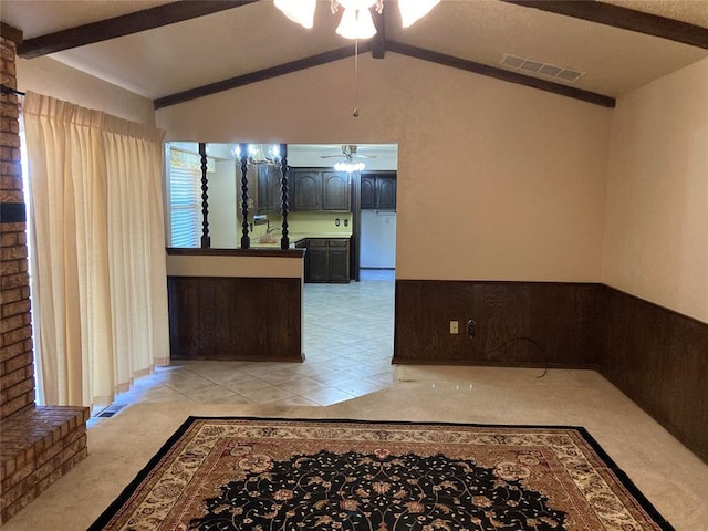 empty room featuring a ceiling fan, lofted ceiling, light carpet, and light tile patterned flooring