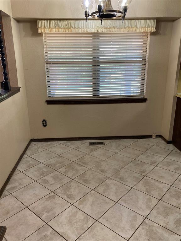 unfurnished dining area featuring a chandelier, plenty of natural light, baseboards, and light tile patterned flooring