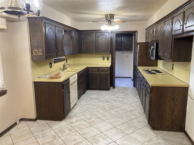 kitchen with a sink, dark brown cabinetry, a textured ceiling, white appliances, and a ceiling fan