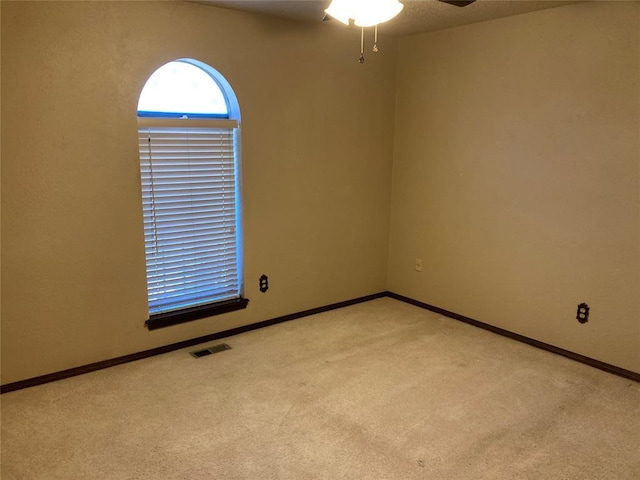empty room with light colored carpet, ceiling fan, and baseboards