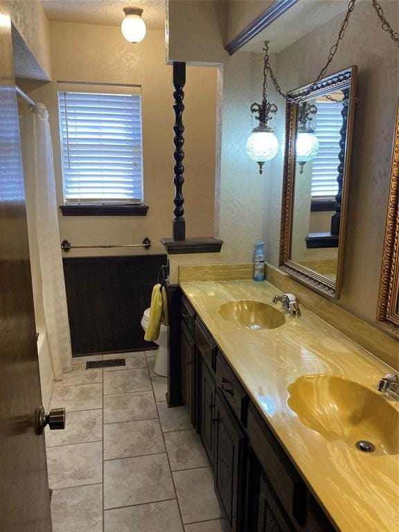 full bathroom featuring healthy amount of natural light, tile patterned floors, curtained shower, and double vanity