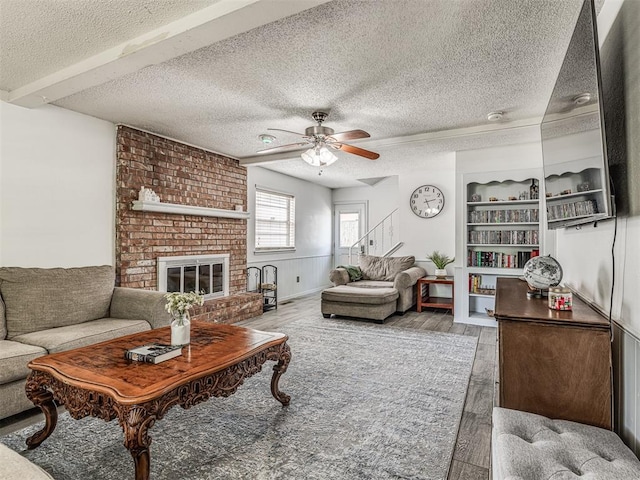 2909 Wheeler Ct, Oklahoma City, OK 73127 - living area with a brick fireplace, wood finished floors, a textured ceiling, and ceiling fan