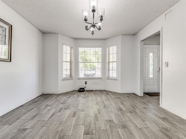 2909 Wheeler Ct, Oklahoma City, OK 73127 - unfurnished dining area with light wood finished floors, baseboards, an inviting chandelier, and a textured ceiling