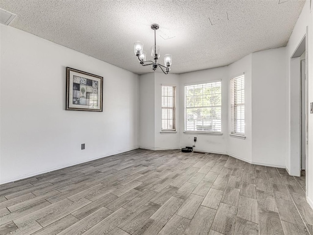 2909 Wheeler Ct, Oklahoma City, OK 73127 - unfurnished room featuring wood finish floors, a textured ceiling, visible vents, and an inviting chandelier