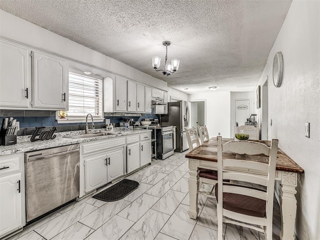 2909 Wheeler Ct, Oklahoma City, OK 73127 - kitchen with a textured ceiling, a sink, an inviting chandelier, stainless steel appliances, and white cabinetry