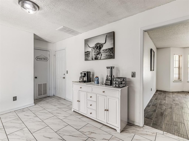 2909 Wheeler Ct, Oklahoma City, OK 73127 - hallway featuring baseboards, visible vents, a textured ceiling, and marble finish floor