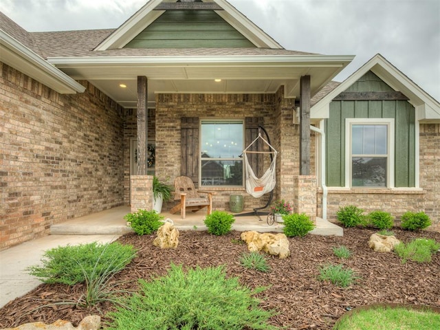 property entrance with a porch, brick siding, and board and batten siding