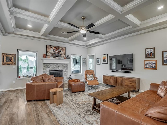living area featuring ornamental molding, ceiling fan, a fireplace, and light wood-type flooring