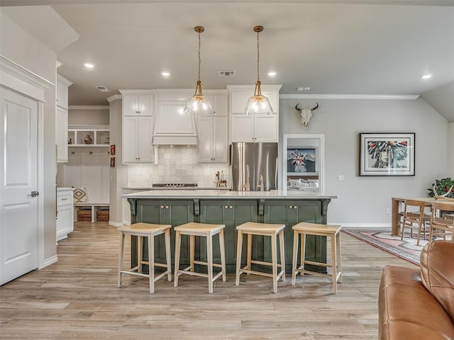 kitchen featuring light countertops, stainless steel appliances, white cabinetry, a kitchen bar, and ornamental molding