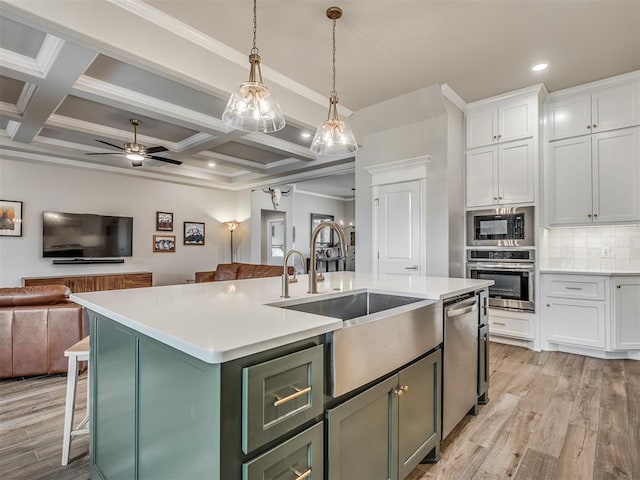 kitchen featuring a sink, white cabinets, open floor plan, stainless steel appliances, and an island with sink