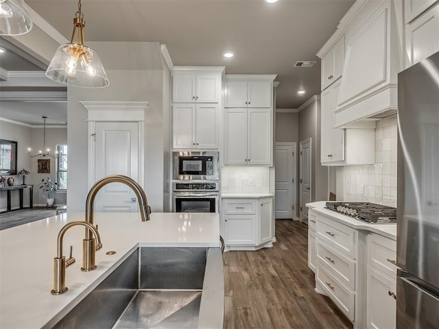 kitchen with appliances with stainless steel finishes, a sink, recessed lighting, visible vents, and ornamental molding