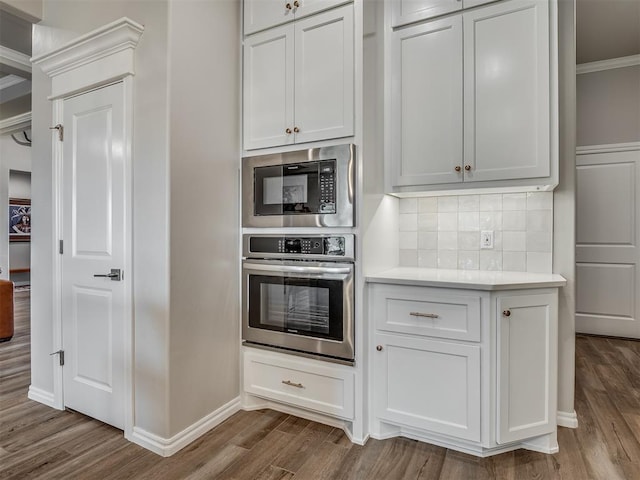 kitchen featuring stainless steel oven, backsplash, built in microwave, and dark wood-style floors