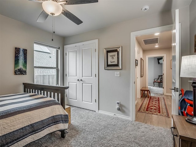 bedroom featuring visible vents, a closet, light carpet, baseboards, and a ceiling fan