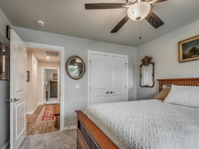 bedroom featuring ceiling fan, light wood finished floors, baseboards, visible vents, and a closet
