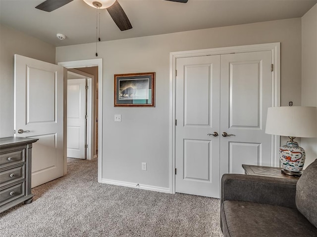 sitting room featuring baseboards, a ceiling fan, and light carpet