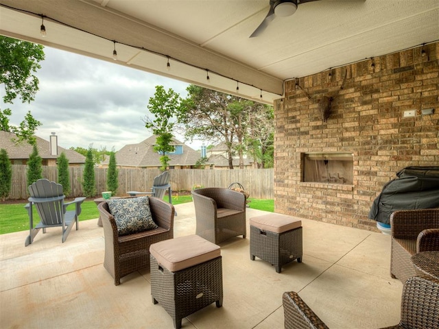 view of patio / terrace featuring a fenced backyard, a ceiling fan, and an outdoor living space with a fireplace