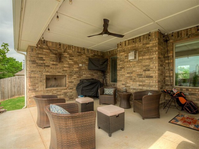 view of patio / terrace featuring a ceiling fan, an outdoor living space with a fireplace, and fence