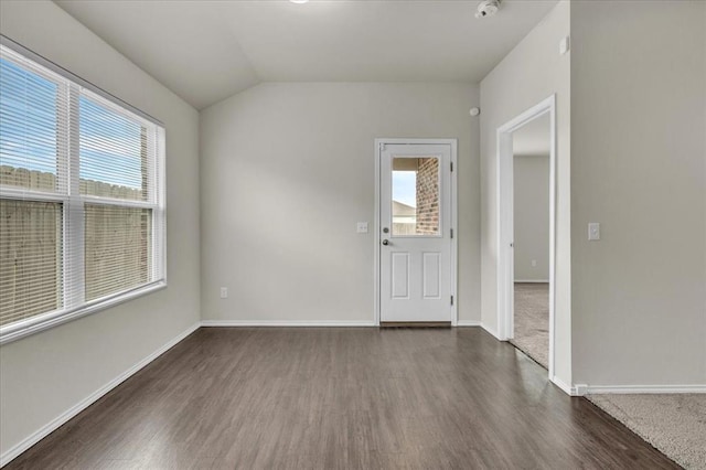 spare room featuring plenty of natural light, baseboards, vaulted ceiling, and dark wood-type flooring