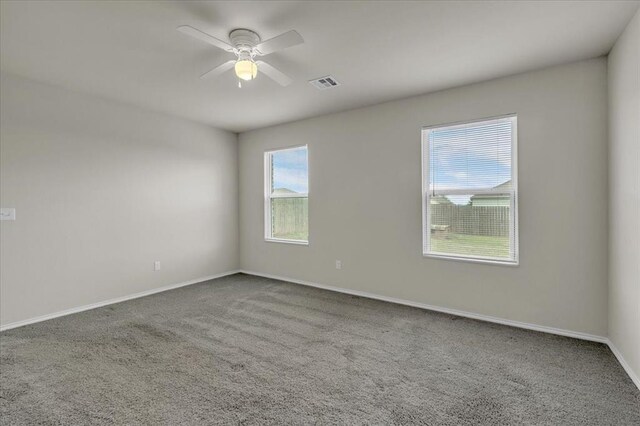 empty room featuring a ceiling fan, visible vents, carpet, and baseboards