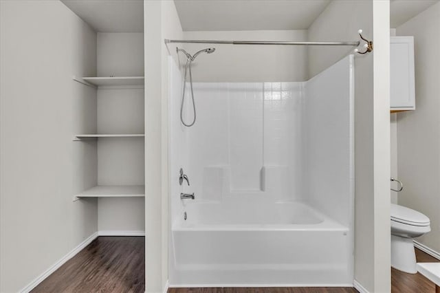 bathroom featuring baseboards, wood finished floors, toilet, and  shower combination