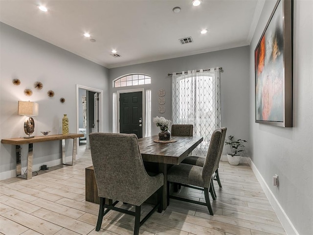 dining space with light wood-type flooring, baseboards, visible vents, and crown molding