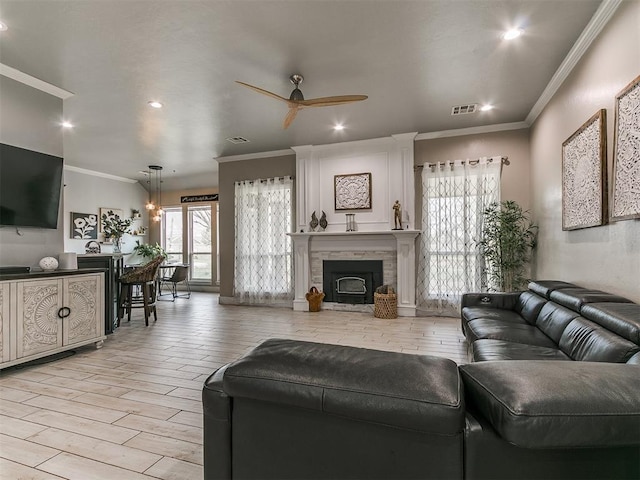 living room with light wood finished floors, visible vents, crown molding, and ceiling fan