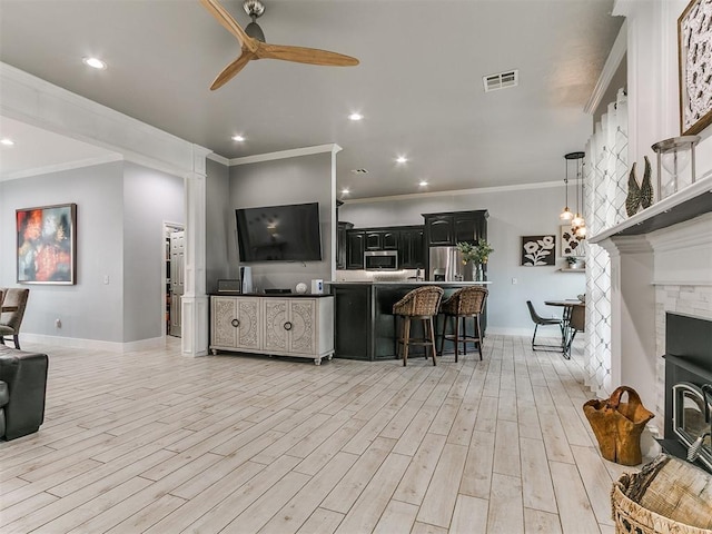 living area featuring a ceiling fan, baseboards, crown molding, and visible vents