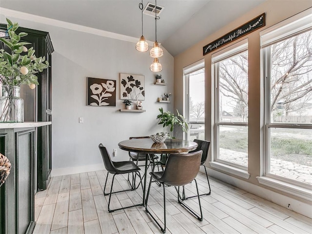 dining room featuring light wood-style floors, vaulted ceiling, visible vents, and a healthy amount of sunlight