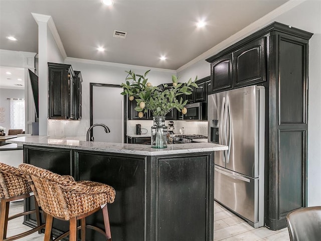kitchen with visible vents, appliances with stainless steel finishes, light stone counters, and dark cabinets