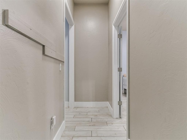 hallway featuring baseboards and light wood-style flooring