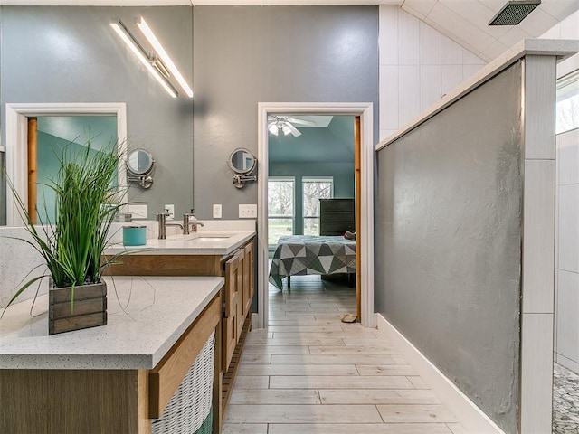 bathroom featuring wood finished floors, connected bathroom, vanity, ceiling fan, and lofted ceiling