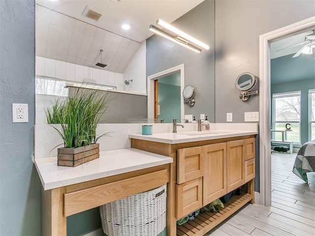 bathroom with vaulted ceiling, visible vents, a textured wall, vanity, and walk in shower
