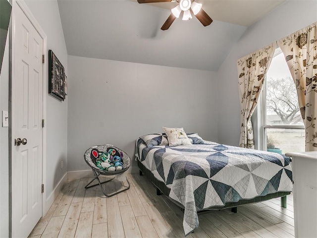 bedroom featuring lofted ceiling, baseboards, wood finished floors, and ceiling fan