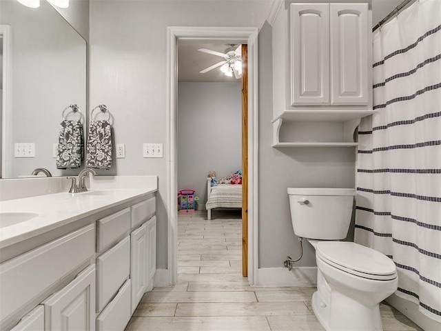 full bath featuring toilet, a sink, ceiling fan, double vanity, and baseboards