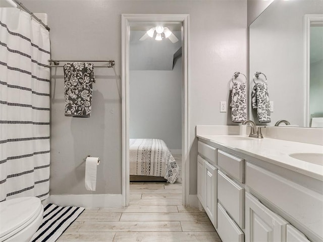 full bath featuring a sink, double vanity, toilet, wood finished floors, and ceiling fan