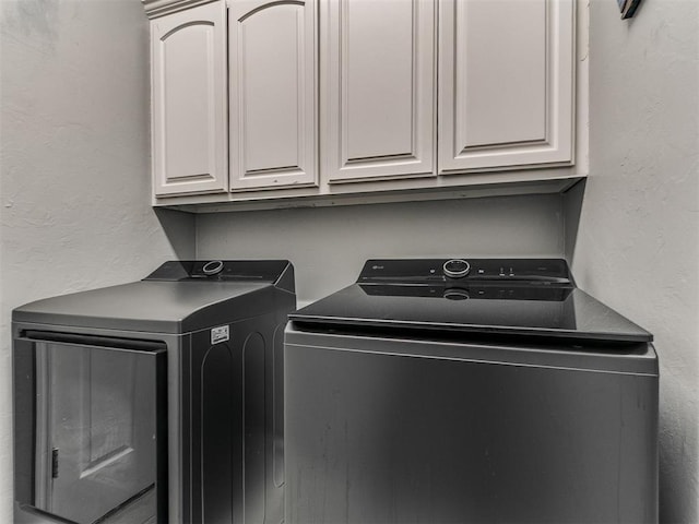 laundry area featuring separate washer and dryer and cabinet space
