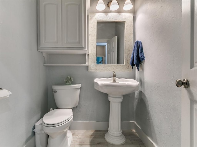 bathroom featuring toilet, wood finished floors, and baseboards