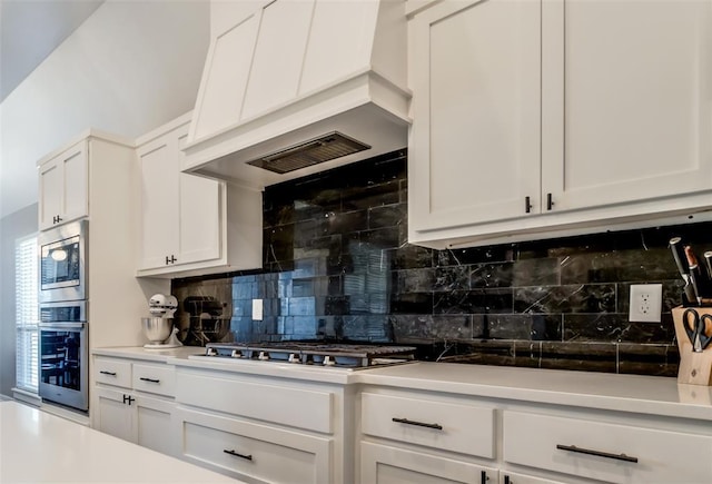 4145 Thunderhead Rd, Norman, OK 73072 - kitchen featuring appliances with stainless steel finishes, custom exhaust hood, tasteful backsplash, white cabinets, and light countertops