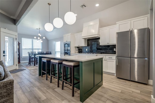 4145 Thunderhead Rd, Norman, OK 73072 - kitchen with stainless steel appliances, premium range hood, an island with sink, light wood finished floors, and recessed lighting