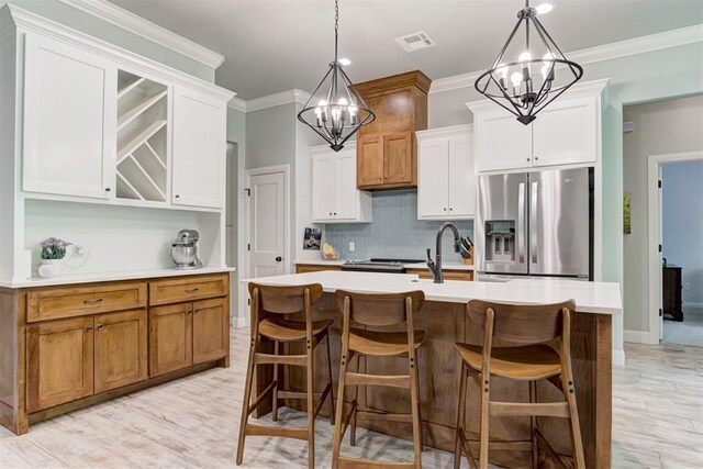 8350 Red Feather, Arcadia, OK 73007 - kitchen with light countertops, visible vents, decorative backsplash, stainless steel fridge, and a notable chandelier