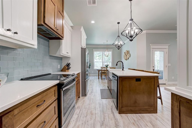 8350 Red Feather, Arcadia, OK 73007 - kitchen with an inviting chandelier, appliances with stainless steel finishes, a center island with sink, ornamental molding, and visible vents