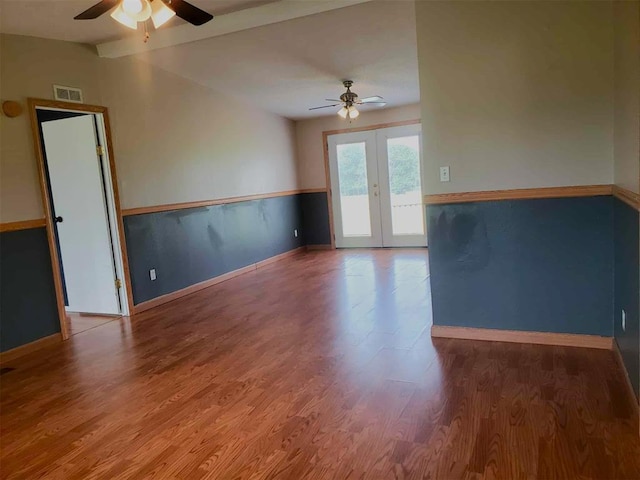 spare room featuring french doors, a ceiling fan, baseboards, wood finished floors, and visible vents