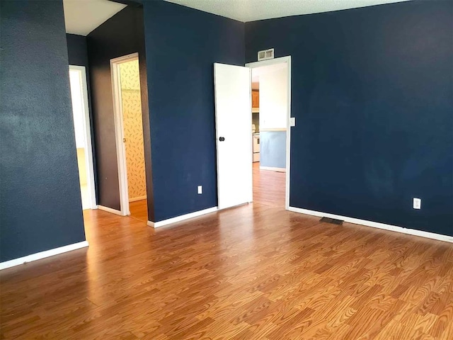 unfurnished room with baseboards, visible vents, and wood finished floors