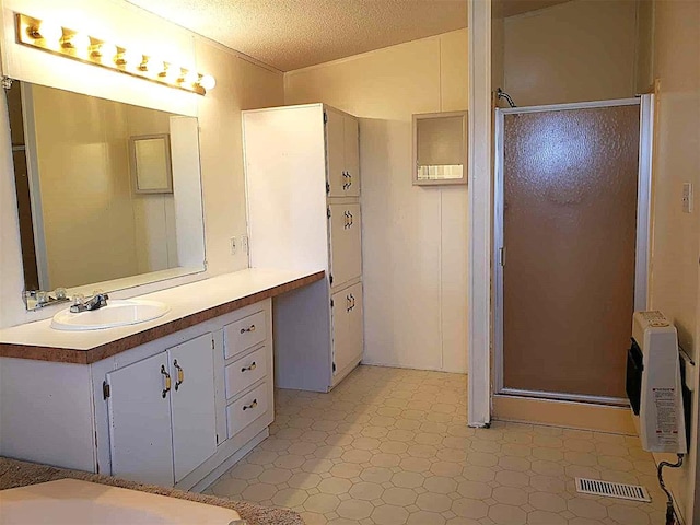 full bath with tile patterned floors, a stall shower, a textured ceiling, and visible vents