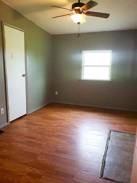spare room featuring baseboards, a textured ceiling, ceiling fan, and wood finished floors