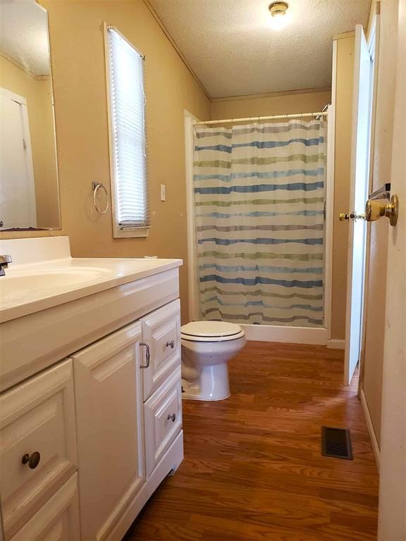 bathroom with visible vents, vanity, wood finished floors, toilet, and a textured ceiling