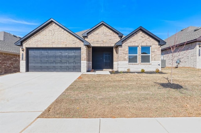 single story home featuring brick siding, an attached garage, a front lawn, and concrete driveway